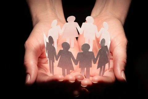 A pair of hands protecting cutout figures of people